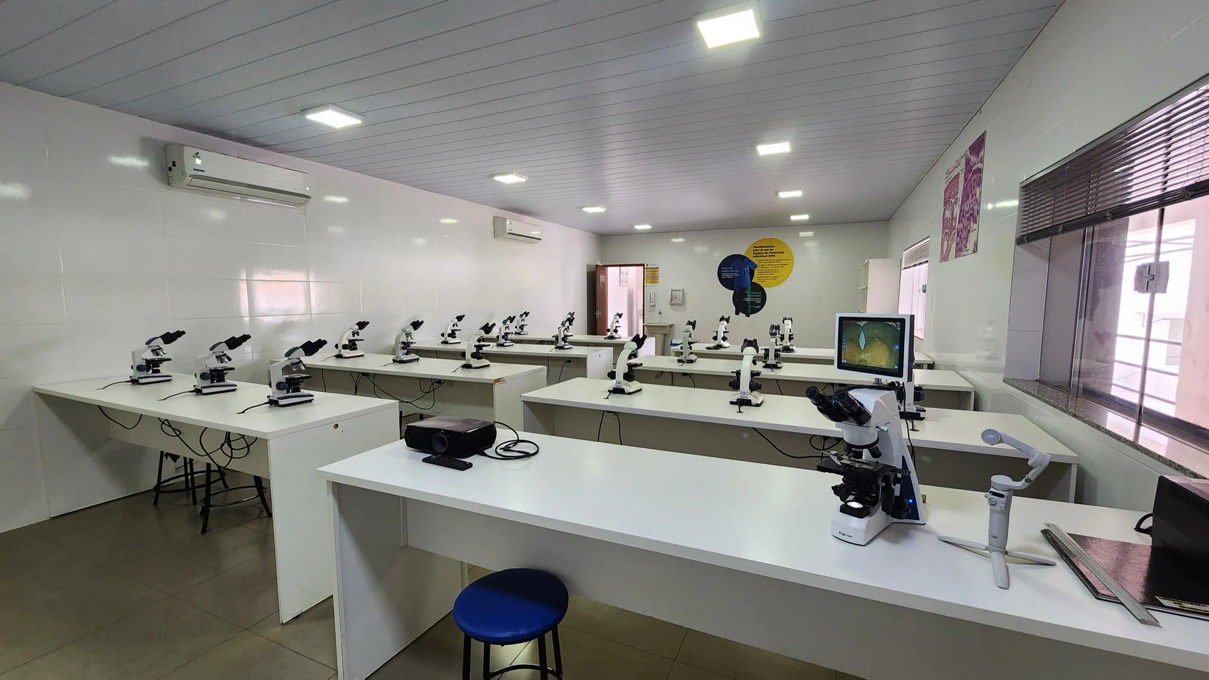 Sala del laboratorio de la UASS-PJC con mesadas blancas, microscopios y monitor