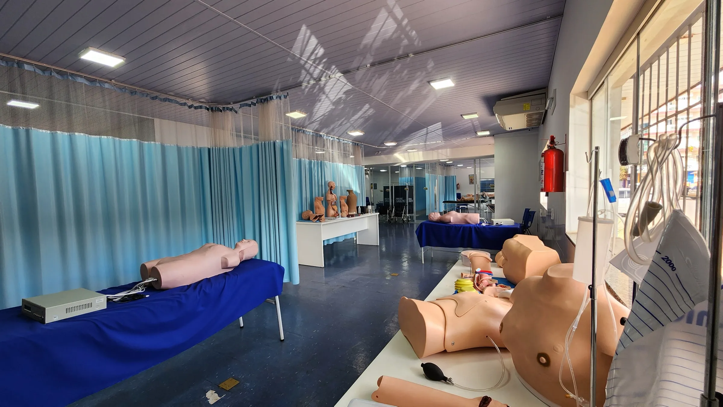 Sala de simulación de la UASS-PJC con simuladores de torso sobre camillas azules y cortinas azules alrededor